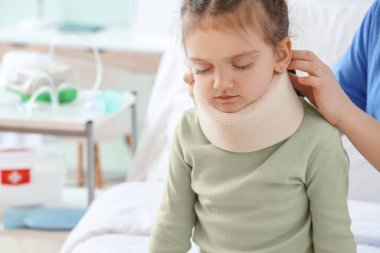 Hemşire klinikte küçük kızın boynuna boyun tasması takıyor.