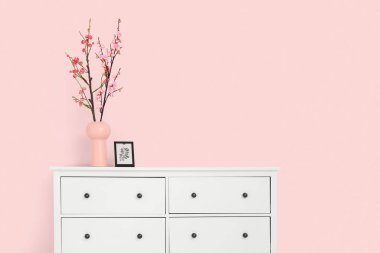 Çiçek açan dalları ve pembe duvarın yanındaki tuvalette çerçevesi olan vazo.