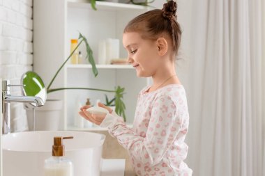 Banyoda lavabonun yanında sabun barlı küçük bir kız.