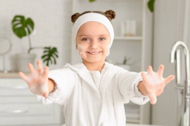 Küçük kız ellerini banyoda yıkıyor.