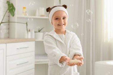 Banyosunda sabun ve köpükler olan küçük bir kız.