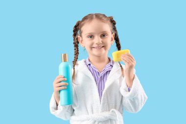 Mavi arka planda sabun çubuğu ve duş jeli olan küçük kız.