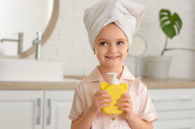 Banyoda duş aldıktan sonra elinde sabun şişesi olan küçük bir kız.