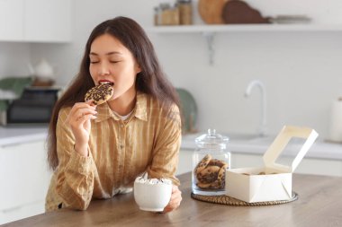 Mutfakta kakaolu kurabiye yiyen genç Asyalı kadın.