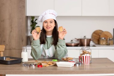Mutfaktaki masada kurabiyeleri olan kadın aşçı.