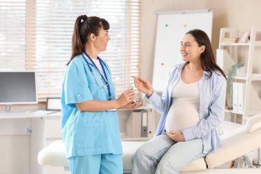 Klinikte glukometre kullanan hamile bir kadın.