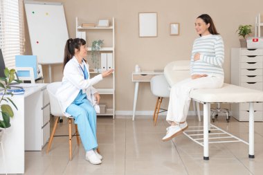 Klinikte hamile bir kadınla çalışan kadın doktor.