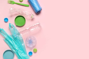 Farklı kapaklı plastik şişeler, çöp torbaları ve pembe arka planda çatal.