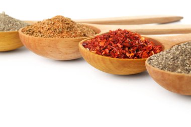 Beyaz arka planda farklı baharatlı tahta kaşıklar, yakın plan.