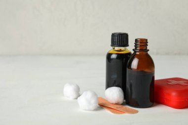 Beyaz arka planda iyot, pamuk topları, ilaç alçıları ve ilk yardım çantası olan şişeler.