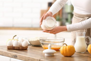 Kadın kaseye şeker ve mutfakta yumurta ekliyor. Yakın çekim.