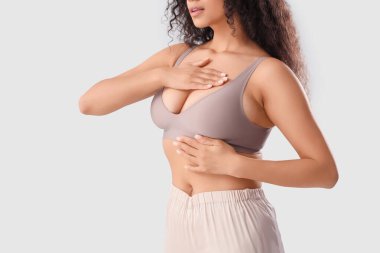 Genç Afro-Amerikalı kadın göğsünü kontrol ediyor, yakın plan. Kanser farkındalığı kavramı