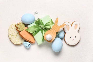 Yumurtalı kompozisyon, hediye kutusu ve beyaz arka planda farklı Paskalya kurabiyeleri.