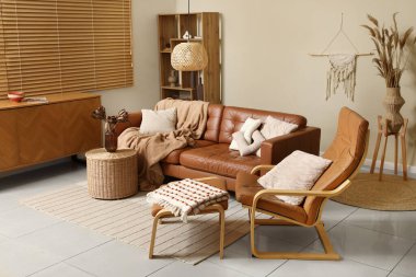 Rahat bir kanepe, ayak sehpası ve vazo içinde kurutulmuş çiçekler oturma odasının iç kısmında sepette.