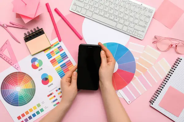 Pembe arka planda boş cep telefonu ve renk paletleri olan kadın grafik tasarımcısı, üst görünüm