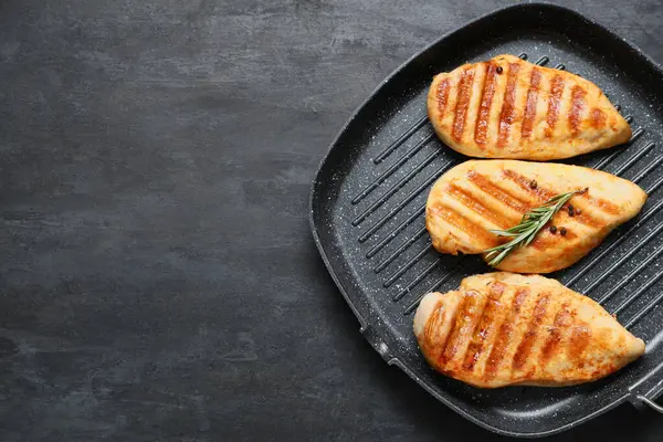 Lezzetli ızgara tavuk göğsü, biberiye ve siyah grunge arka planda biberiye ile kızartma tavası.