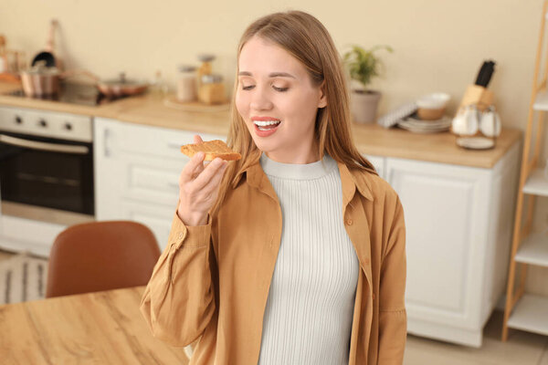 Young woman eating toast with peanut butter in kitchen