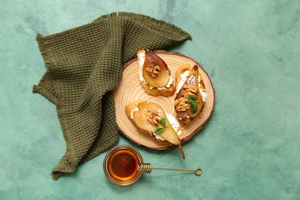 Armut bruschetta tahtası, ricotta peyniri, ceviz ve bal, yeşil arka planda.