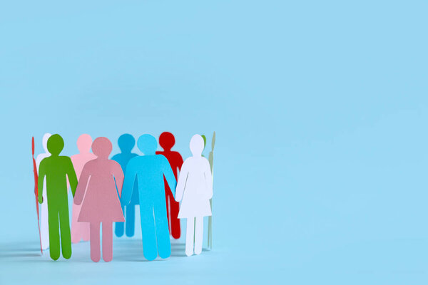Бумажные человеческие фигуры образуют круг на цветном фоне. Концепция разнообразия и интеграции