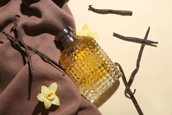 Renkli arkaplanda parfüm şişesi, vanilya çubuğu ve kumaş kompozisyonu