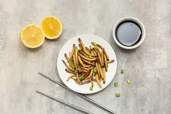Bir tabak yeşil soğanlı, limonlu ve arka planda soya soslu kızarmış kurtçuk.