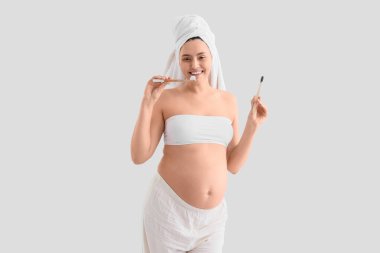 Arka planda diş fırçası olan hamile bir kadın.