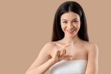 Bej arka planda ampulü olan güzel bir genç kadın, yakın plan.