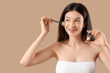 Ampul ve bej arka planda fırçası olan güzel genç bir kadın.