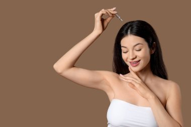 Kahverengi arka planda ampulü olan güzel bir genç kadın.