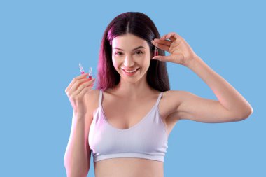 Mavi arka planda ampulleri olan güzel genç bir kadın.