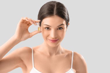 Hafif arka planda ampulü olan genç bir kadın, yakın plan.