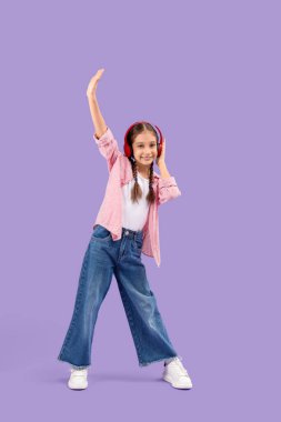 Kulaklıklı tatlı kız leylak arka planda dans ediyor.