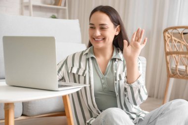 Evde dizüstü bilgisayarı olan güzel bir kadın sohbet ediyor.