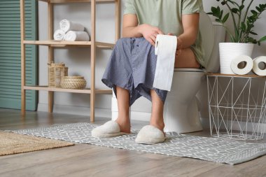 Tuvaletteki klozete kağıt rulo yapıştırmış bir adam.