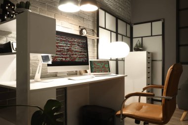 Programcının işyeri, gece ofiste cihazlar ve parlayan lambalarla.