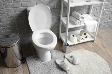 Tuvalet, çöp tenekesi ve raf ünitesi olan bir tuvalet.