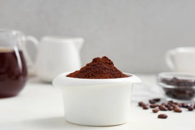 Bir kase kahve tozu ve açık arkaplan fasulyesi.