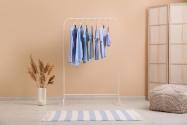 Süslü giysiler, puf ve katlanan ekran ile rafa kaldırın oda bej duvar yanında