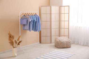 Süslü giysiler, puf ve katlanan ekran ile rafa kaldırın oda bej duvar yanında