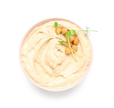 Beyaz zemin üzerinde nohut ve mikro yeşil olan lezzetli humus kasesi.