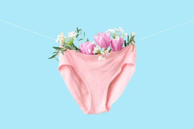 Çamaşır ipinde mavi arka planda asılı çiçekli kadın külotu