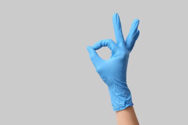 Tıbbi eldivenli kadın eli gri arka planda iyi görünüyor.