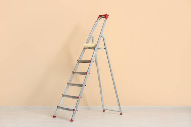 Bej duvarın yanındaki bakım merdiveni.