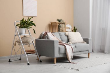 Gri kanepesi, merdiveni ve raf ünitesi olan şık bir oda.