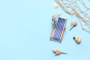 Mavi arka planda deniz kabukları olan küçük bir şezlong. Yaz konsepti
