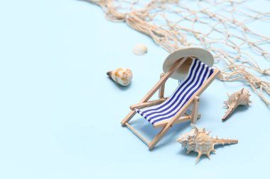 Mavi arka planda deniz kabukları olan küçük bir şezlong. Yaz konsepti