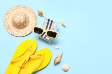 Parmak arası terlikleri, hasır şapkası ve mavi arka planda deniz kabukları olan mini bir iskemle. Yaz konsepti