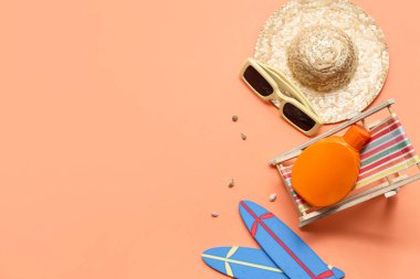 Güverte sandalyeli mini sörf tahtaları, güneş kremi ve turuncu arka planda hasır şapka. Yaz konsepti