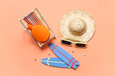 Güverte sandalyeli mini sörf tahtaları, güneş kremi ve turuncu arka planda hasır şapka. Yaz konsepti
