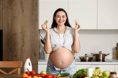 Mutfakta salatalık dilimleri olan hamile bir kadın.